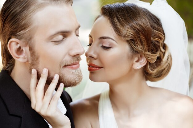 Jóvenes hermosos recién casados sonriendo con los ojos cerrados, disfrutando.