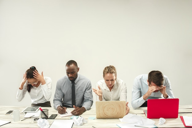 Jóvenes hombres y mujeres africanos y caucásicos sentados en la oficina y trabajando en ordenadores portátiles. El negocio, las emociones, el equipo, el trabajo en equipo, el lugar de trabajo, el liderazgo, el concepto de reunión. diferentes emociones de colegas