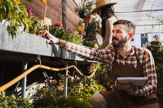 Jóvenes jardineros rociando plantas y tomando notas