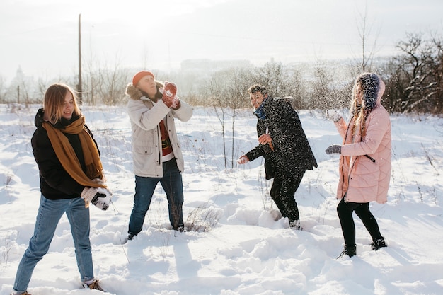 Jóvenes jugando bolas de nieve en el bosque de invierno