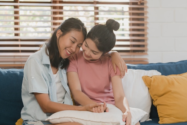 Jóvenes lesbianas lgbtq mujeres asiáticas pareja abrazan y besan en casa