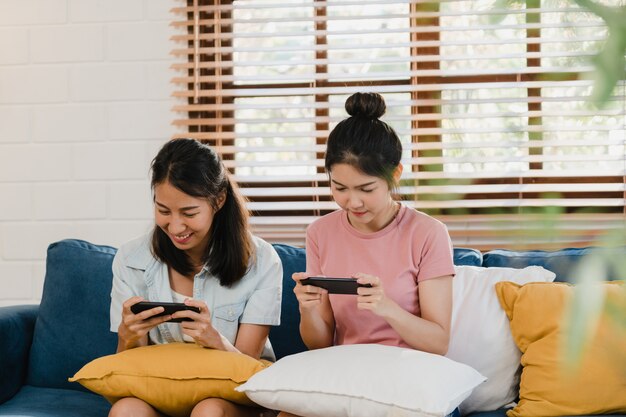 Jóvenes lesbianas lgbtq mujeres pareja usando el teléfono móvil en casa