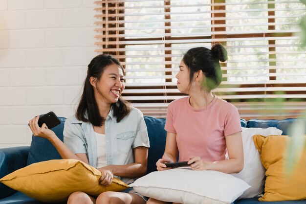 Jóvenes lesbianas lgbtq mujeres pareja usando el teléfono móvil en casa