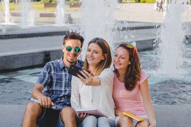 Jóvenes con libros de texto tomando selfie