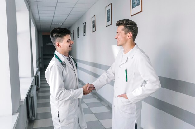 Jóvenes médicos dándose la mano en el pasillo