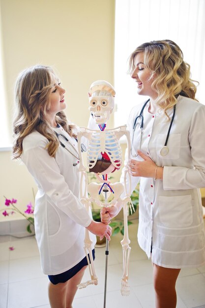 Jóvenes médicos divirtiéndose posando con esqueleto