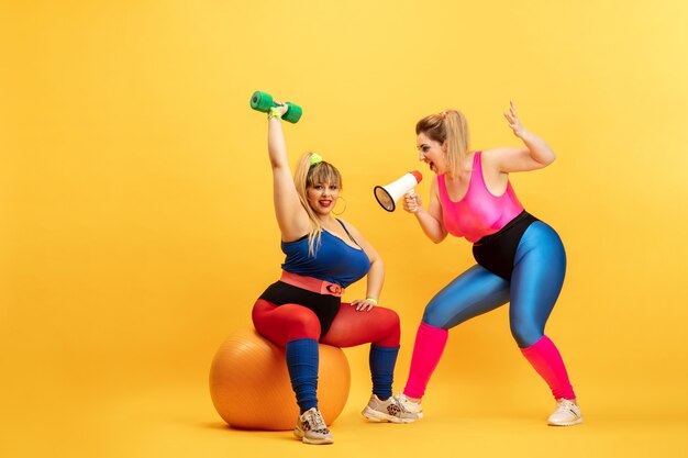 Jóvenes modelos femeninos caucásicos de talla grande entrenando en amarillo