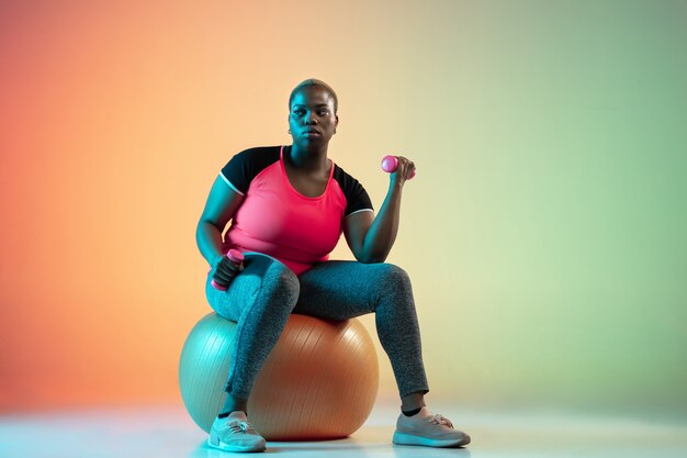 Jóvenes modelos femeninos de talla grande afroamericanos entrenando en pared degradada