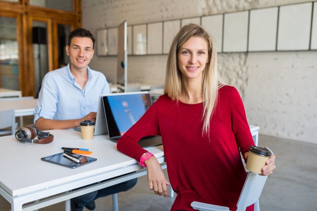 Los jóvenes modernos sentados a la mesa, trabajando en la computadora portátil en la oficina de trabajo conjunto