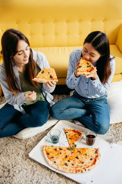 Jóvenes mujeres escalofriantes disfrutando de pizza