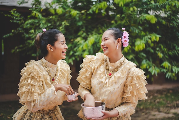 Jóvenes mujeres sonrientes se visten con hermosos trajes tailandeses salpicando agua en los templos y preservan la buena cultura de los tailandeses durante el festival songkran, día de la familia del año nuevo tailandés en abril