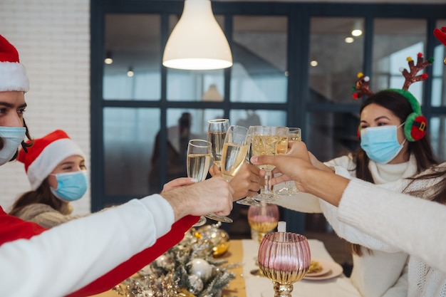 Jóvenes multiétnicos celebrando la víspera de Año Nuevo tintineando vasos brindando, amigos multirraciales divirtiéndose en la celebración de la fiesta, felicitando bebiendo champán