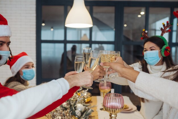 Jóvenes multiétnicos celebrando la víspera de Año Nuevo tintineando vasos brindando, amigos multirraciales divirtiéndose en la celebración de la fiesta, felicitando bebiendo champán