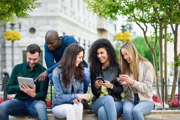 Jóvenes multiétnicos que usan computadoras con teléfonos inteligentes y tabletas