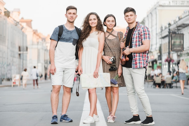 Jóvenes de pie en la calle con mapa y cámara