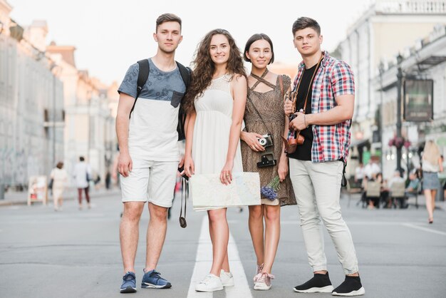 Jóvenes de pie en la calle con mapa y cámara