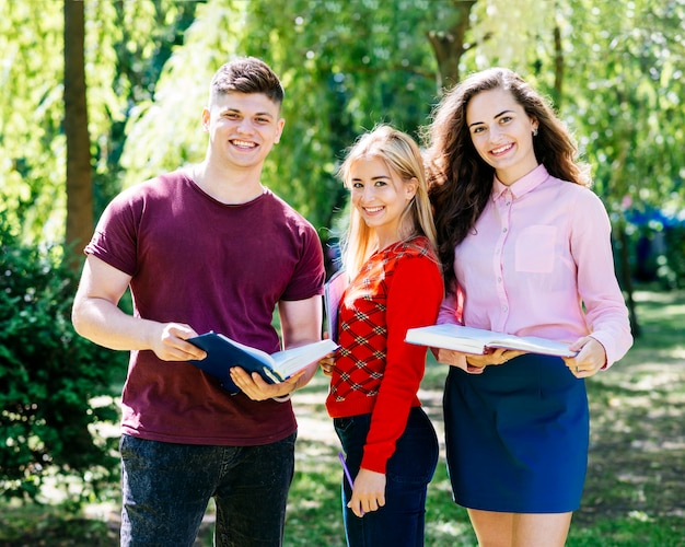 Jóvenes de pie en el parque con libros