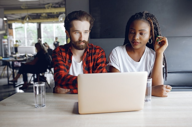 Jóvenes que trabajan juntos y usan la computadora portátil