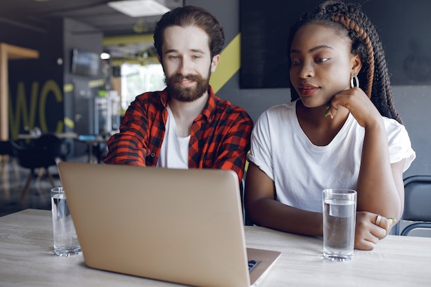 Jóvenes que trabajan juntos y usan la computadora portátil