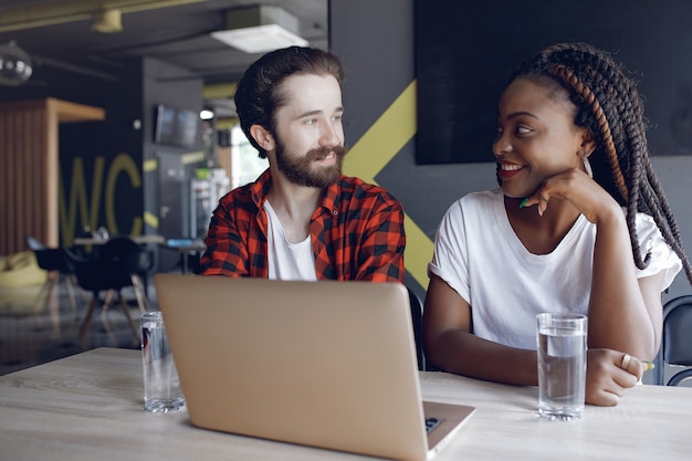 Jóvenes que trabajan juntos y usan la computadora portátil