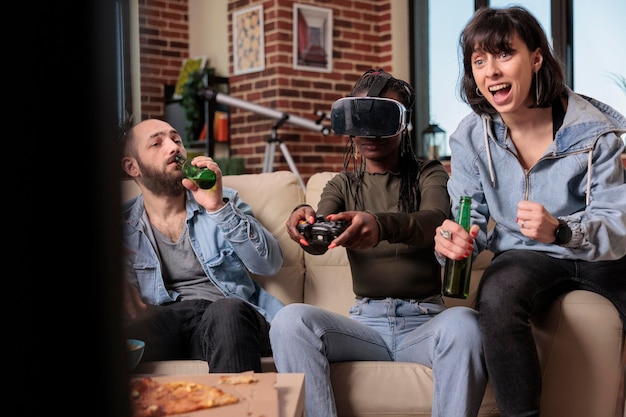 Jóvenes que usan gafas vr para jugar videojuegos en una divertida reunión en casa, jugando a la competencia en la televisión. Disfrutando de actividades de ocio con botellas de cerveza y bocadillos, fiesta de juegos en 3d.