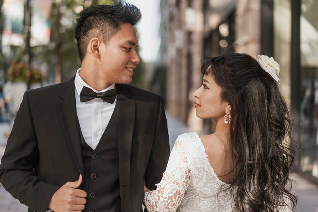 Jóvenes recién casados posando juntos al aire libre