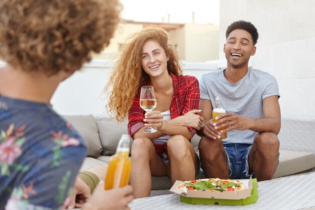 jóvenes reunidos juntos sentados en un cómodo sofá teniendo una conversación interesante