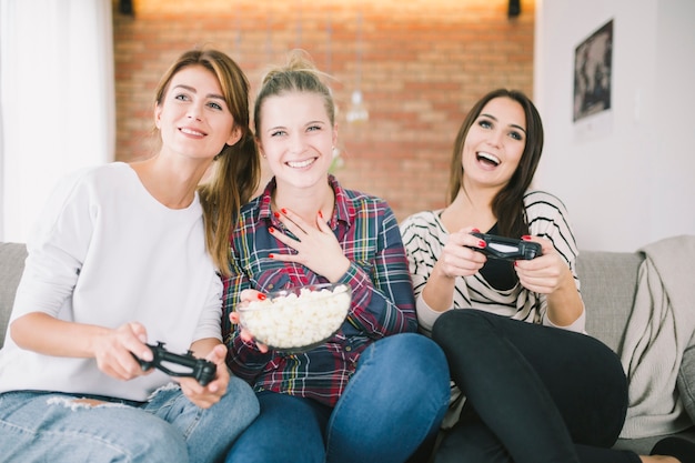 Jóvenes riendo a mujeres jugando viodegame en casa