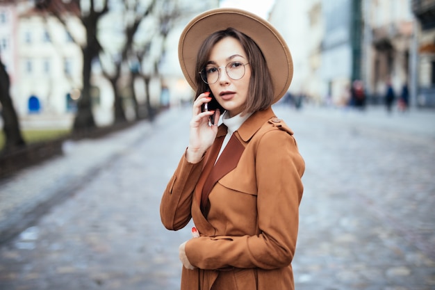 Jóvenes con sombrero ancho hablando en la calle otoño smartphone