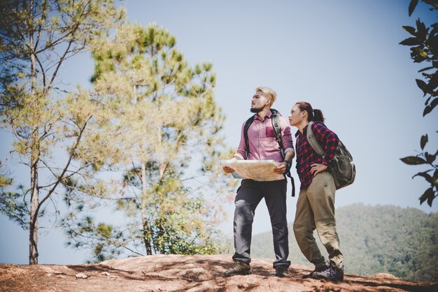 Jóvenes turista pareja viajando de vacaciones en la montaña mirando el mapa en busca de atracciones. Concepto de viaje.