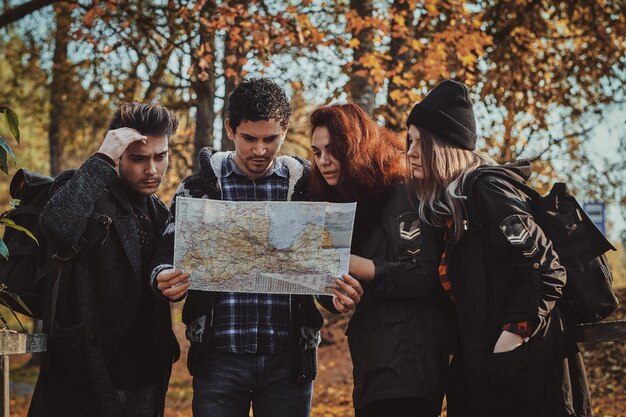 Los jóvenes turistas, hombres y mujeres, están tratando de entender dónde están, usando un mapa.