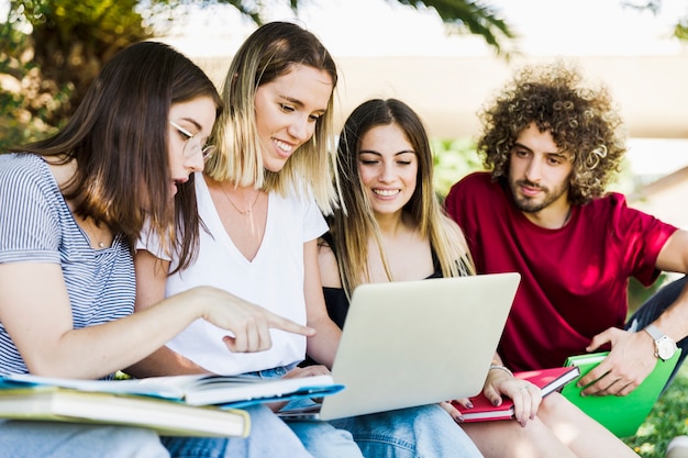 Foto gratuita jóvenes usando la computadora portátil en el parque