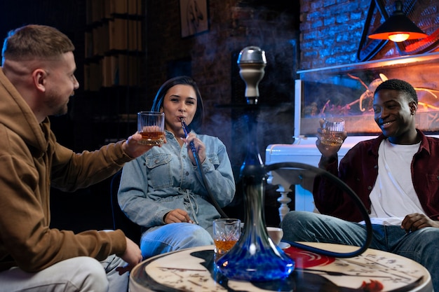 Foto gratuita jóvenes vapeando desde una pipa de agua en un bar.