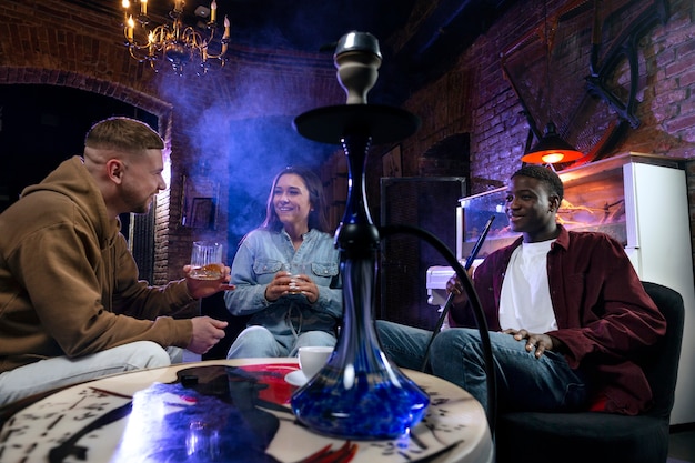 Jóvenes vapeando desde una pipa de agua en un bar.