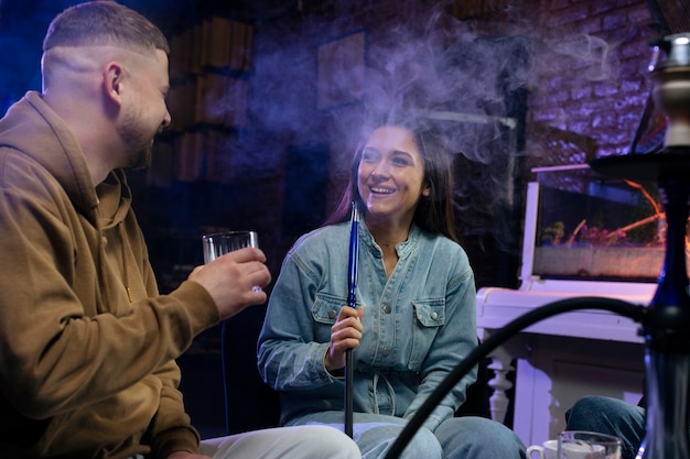 Jóvenes vapeando desde una pipa de agua en un bar.