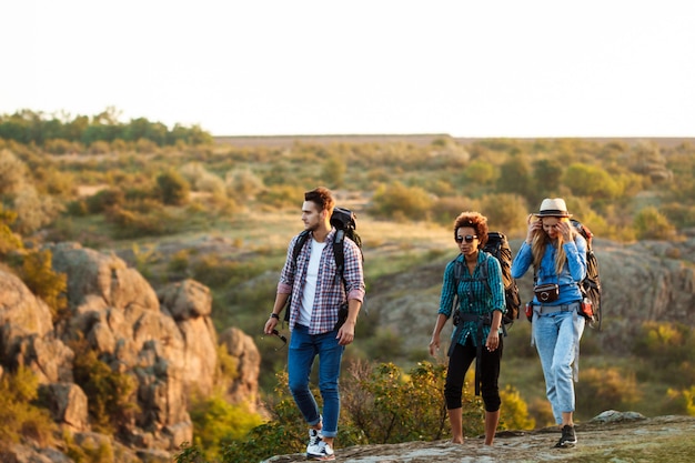 Jóvenes viajeros alegres con mochilas sonriendo, caminando en el cañón