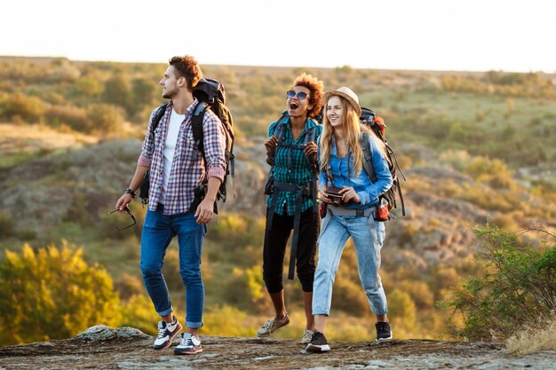 Jóvenes viajeros alegres con mochilas sonriendo, caminando en el cañón
