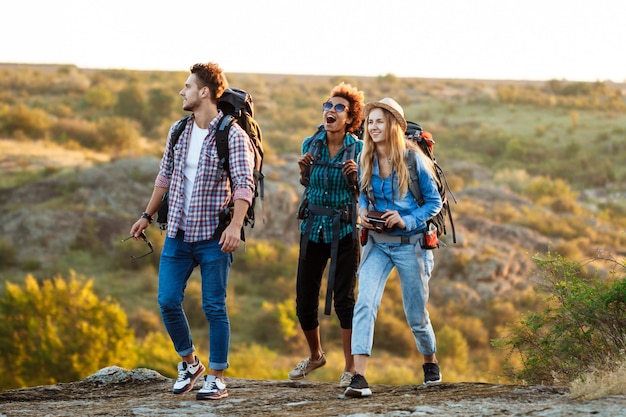 Jóvenes viajeros alegres con mochilas sonriendo, caminando en el cañón