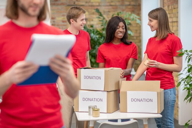 Jóvenes voluntarios con camisetas rojas en el trabajo en un punto de distribución