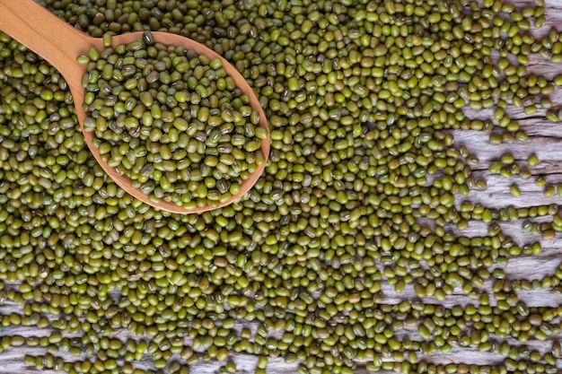 Judías verdes crudas en una taza colocada en un piso de madera.