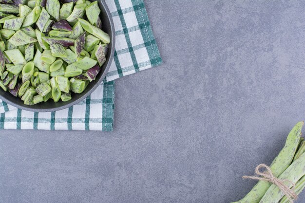 Judías verdes oscuras aisladas en un plato en la superficie