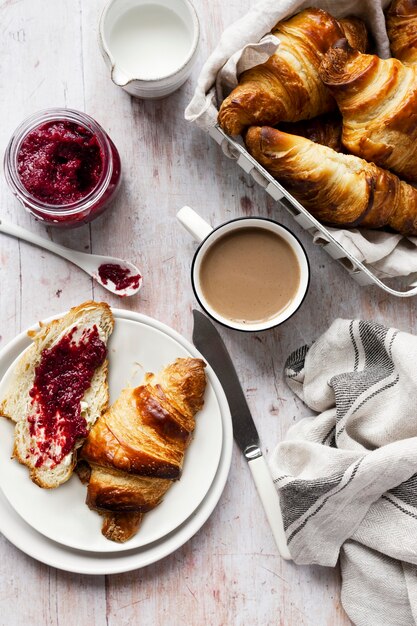 Juego de desayuno plano con croissant y mermelada de frambuesa fotografía de alimentos