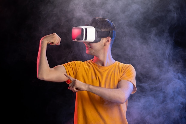 Juego masculino guapo en realidad virtual en superficie oscura