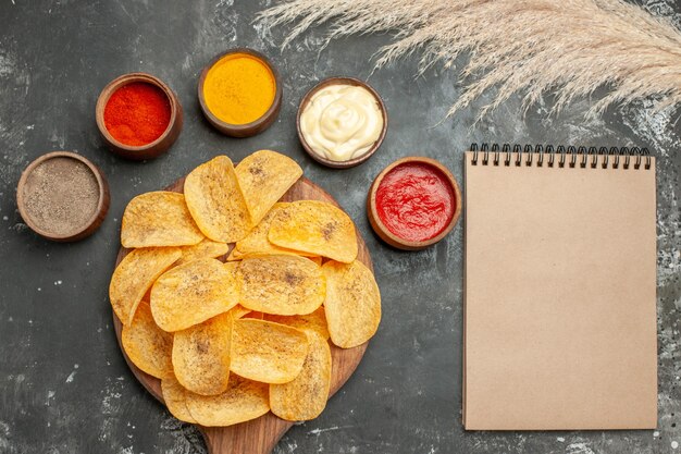 Juego para papas fritas que contienen diferentes especias mayonesa y salsa de tomate junto al cuaderno