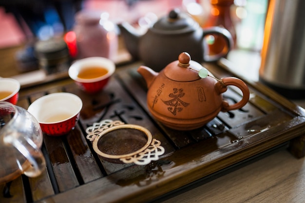 Juego de té chino con colador metálico en bandeja de madera.