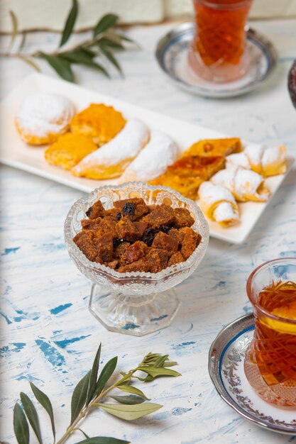 Juego de té con variedades de nueces tradicionales, limón, confitura y dulces servidos sobre un mantel blanco