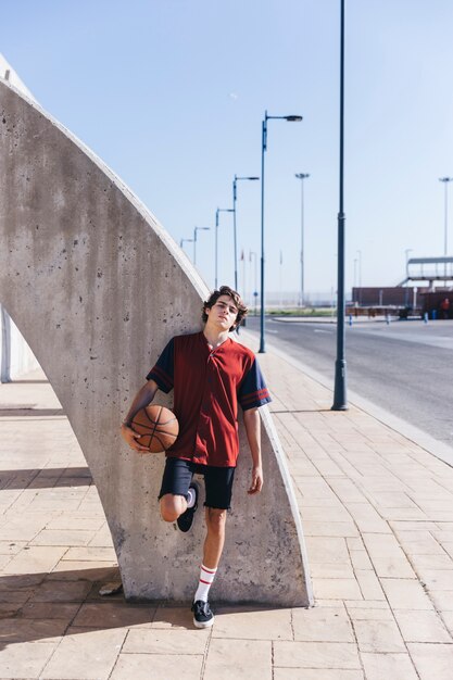 Jugador apoyado en la pared con baloncesto