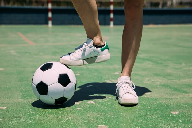 Jugador con balón de fútbol con pierna en estadio