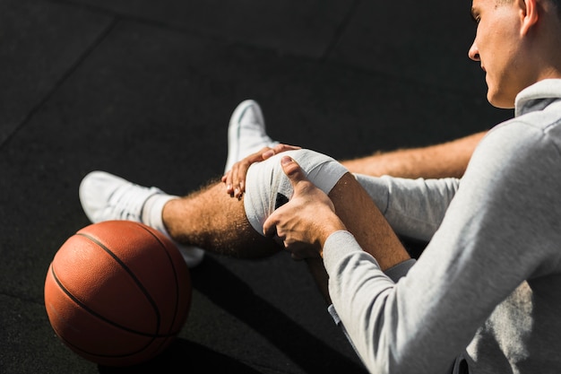 Jugador de baloncesto aplicando vendaje en la rodilla