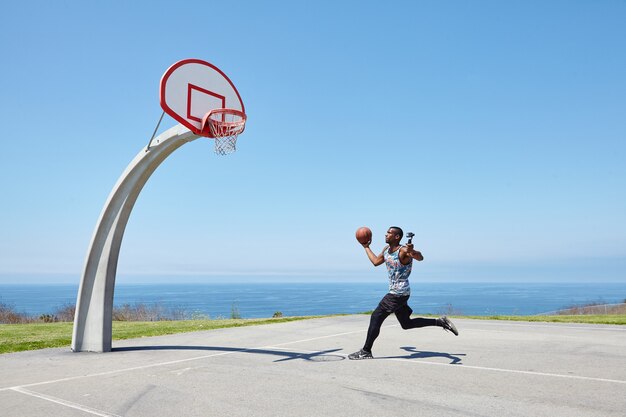 Jugador de baloncesto corriendo por el océano con cámara selfie